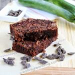 Gluten-free chocolate zucchini bread, a green zuchini and a dish with semisweet chocolate chunks