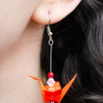 Wearing a red beaded origami earring shaped like a paper crane