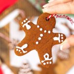 hand holding a homemade cinnamon ornament shaped like a gingerbread man.